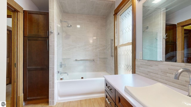 bathroom with vanity, tiled shower / bath combo, wood-type flooring, and tile walls