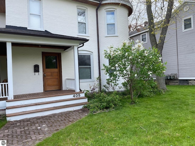 entrance to property featuring a lawn and a porch