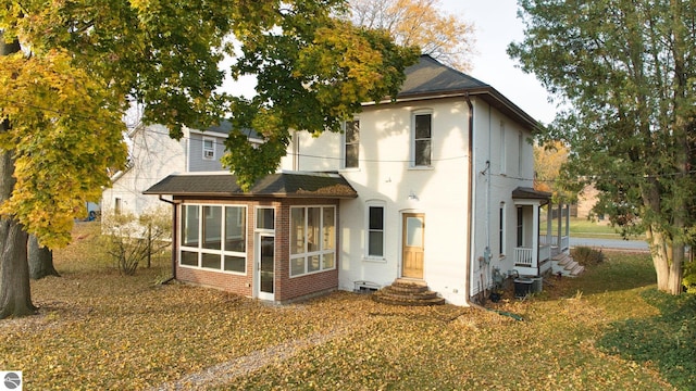 rear view of house with central air condition unit and a sunroom