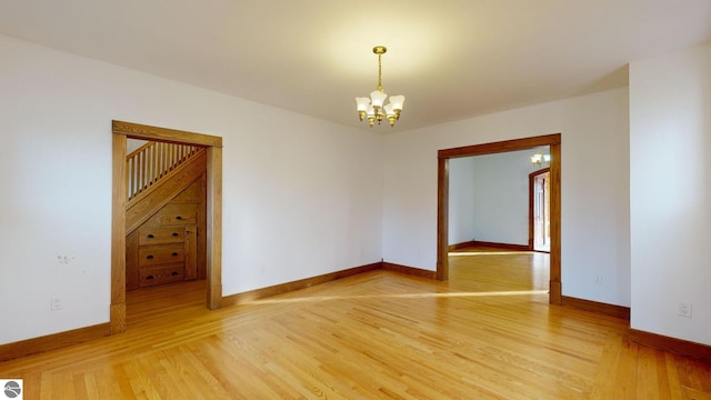 empty room with a notable chandelier and wood-type flooring