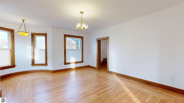 empty room with a notable chandelier and hardwood / wood-style floors