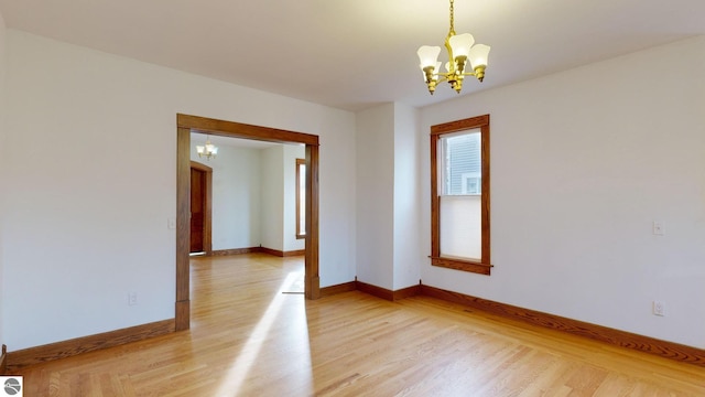 spare room with light hardwood / wood-style flooring and a chandelier