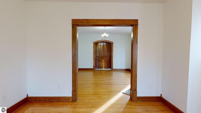 corridor with an inviting chandelier and wood-type flooring