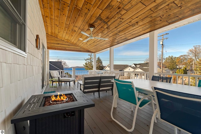 wooden deck with ceiling fan and an outdoor living space with a fire pit