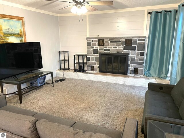 carpeted living room featuring a stone fireplace, wood walls, a textured ceiling, and ceiling fan