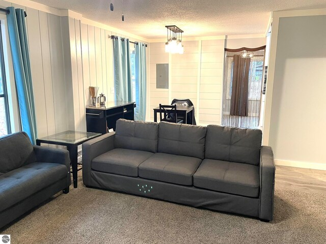 living room with ornamental molding, a textured ceiling, electric panel, and wood-type flooring