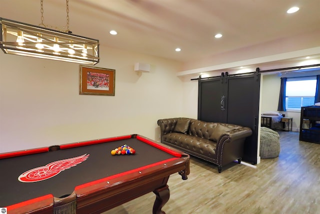 recreation room with a barn door, pool table, and hardwood / wood-style flooring