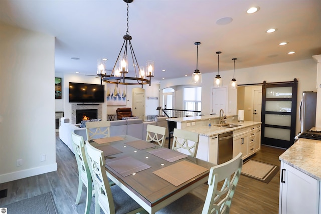 dining area with sink, a barn door, dark hardwood / wood-style floors, and a chandelier