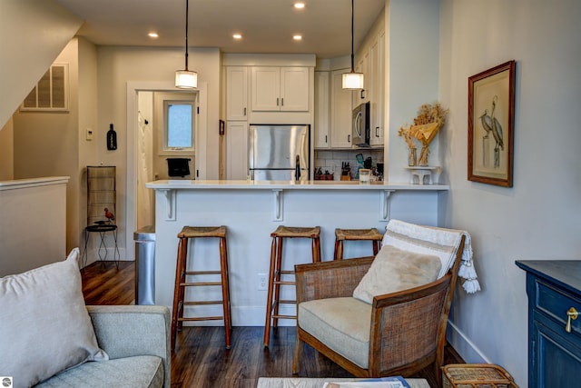 kitchen with appliances with stainless steel finishes, a kitchen bar, and pendant lighting