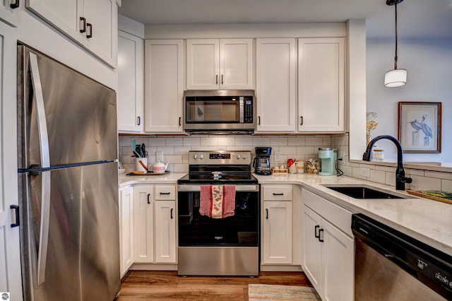 kitchen with sink, white cabinetry, hanging light fixtures, and stainless steel appliances