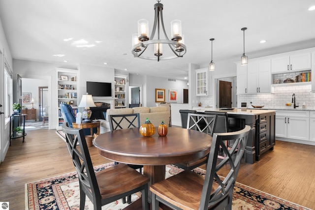 dining space with a chandelier, light hardwood / wood-style floors, built in features, and sink