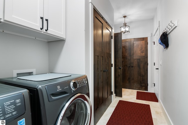 clothes washing area with cabinets and washing machine and dryer