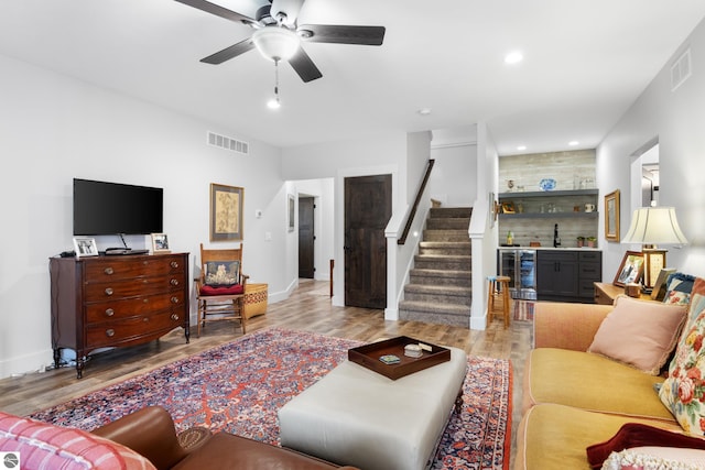 living room with ceiling fan, light wood-type flooring, wine cooler, and bar area