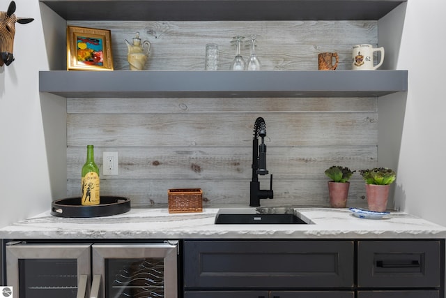 bar featuring backsplash, light stone counters, and sink