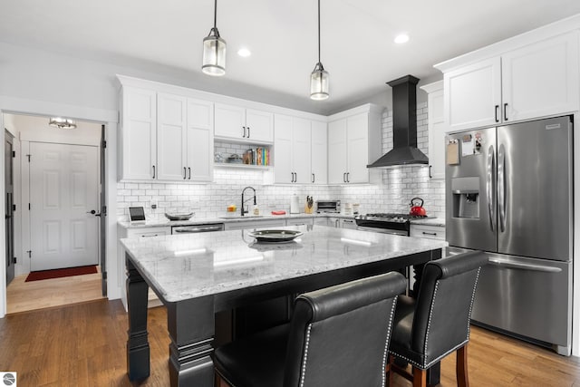 kitchen with backsplash, wall chimney exhaust hood, a center island, and stainless steel appliances