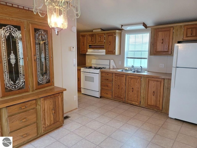 kitchen featuring decorative light fixtures, a notable chandelier, exhaust hood, sink, and white appliances