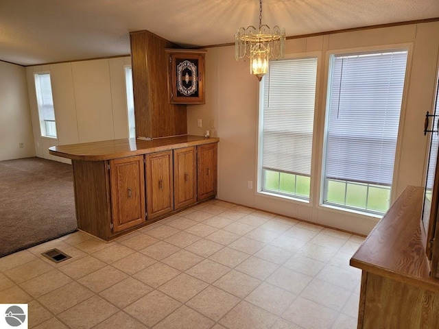 kitchen with kitchen peninsula, a textured ceiling, light carpet, pendant lighting, and a chandelier