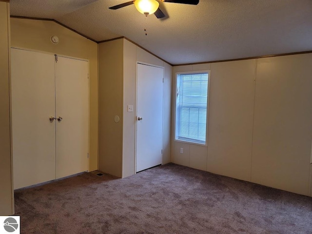 unfurnished bedroom featuring lofted ceiling, a textured ceiling, light carpet, and ceiling fan