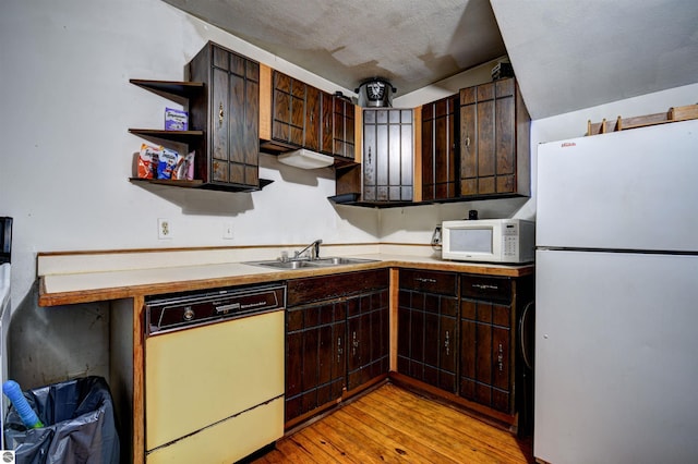 kitchen featuring dark brown cabinetry, a textured ceiling, sink, light wood-type flooring, and white appliances