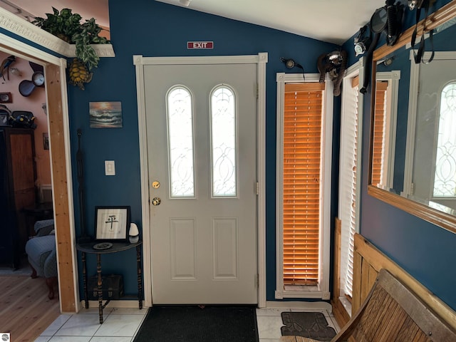 foyer featuring light tile patterned floors and vaulted ceiling