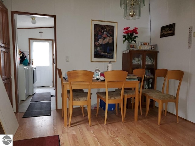 dining space with washer / dryer, light hardwood / wood-style flooring, and vaulted ceiling