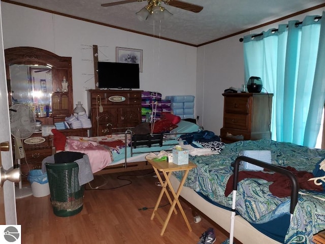 bedroom featuring hardwood / wood-style floors, ceiling fan, and crown molding