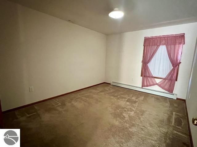 spare room with baseboard heating and carpet flooring