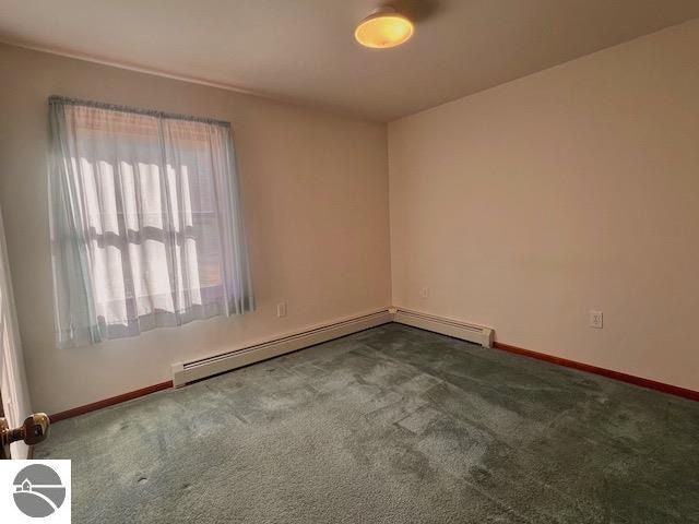 spare room featuring dark carpet and a baseboard radiator