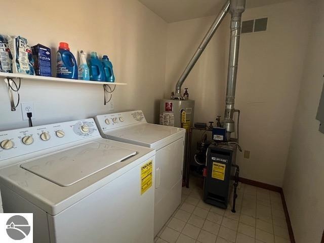 washroom with washer and clothes dryer, water heater, and light tile patterned floors