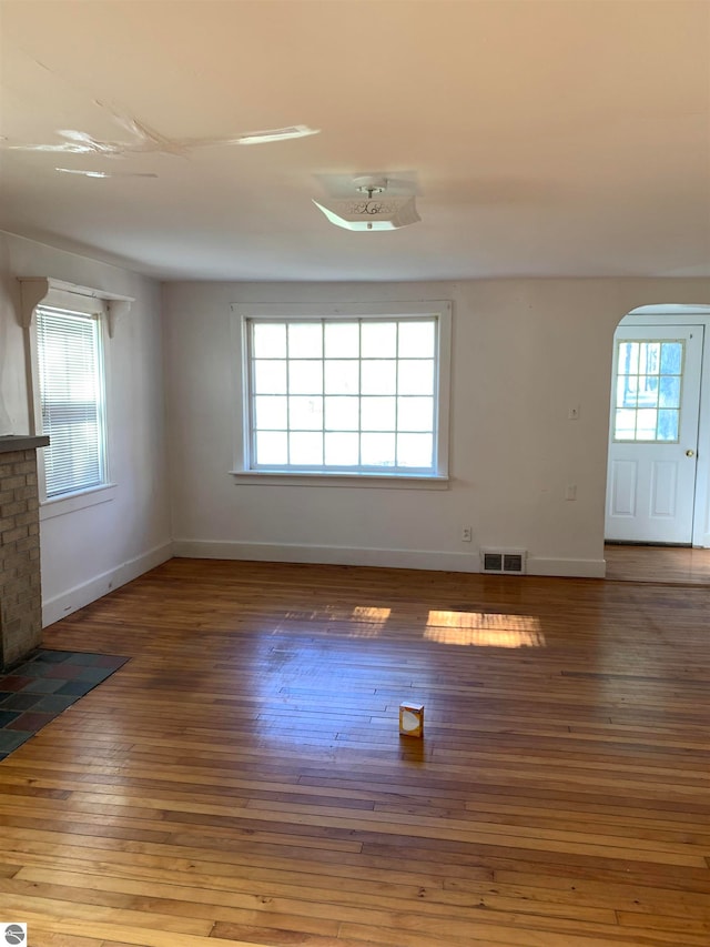 spare room with hardwood / wood-style floors and a brick fireplace