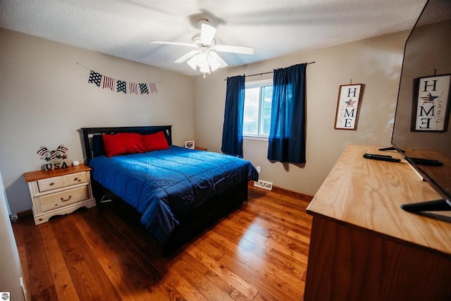 bedroom with a textured ceiling, ceiling fan, and dark hardwood / wood-style floors