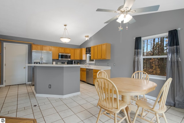 kitchen featuring stainless steel appliances, vaulted ceiling, light tile patterned floors, ceiling fan, and a kitchen island