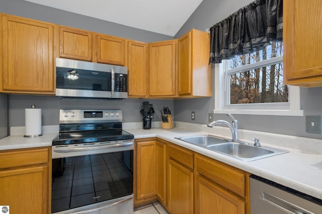 kitchen with stainless steel appliances, light tile patterned floors, sink, and vaulted ceiling