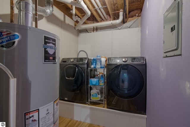 laundry room with water heater, electric panel, wood-type flooring, and washing machine and clothes dryer