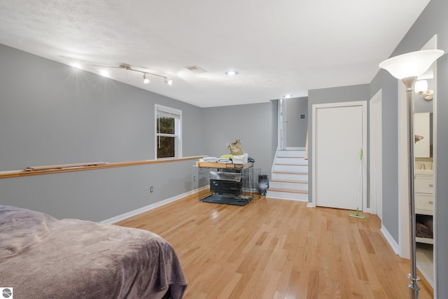 bedroom with connected bathroom and light wood-type flooring