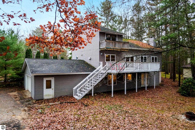 rear view of house with a balcony, a garage, and a wooden deck