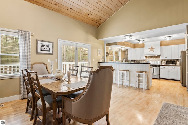 dining room with light hardwood / wood-style floors, wood ceiling, and high vaulted ceiling