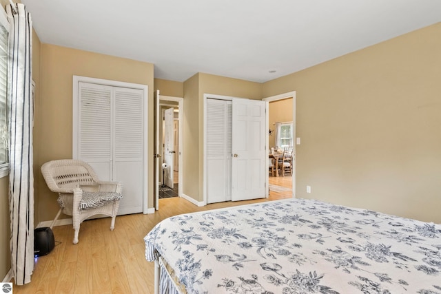 bedroom featuring multiple closets and light hardwood / wood-style flooring