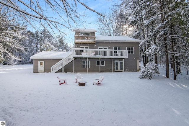 snow covered house with french doors and a wooden deck