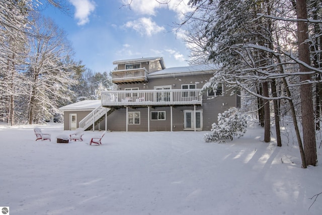 snow covered house with french doors and a deck