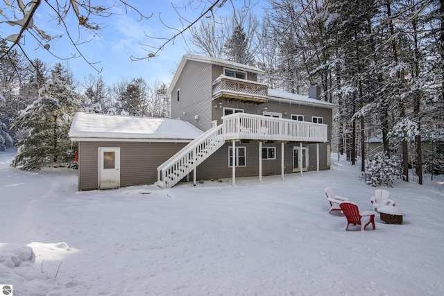 snow covered rear of property featuring an outbuilding and a deck