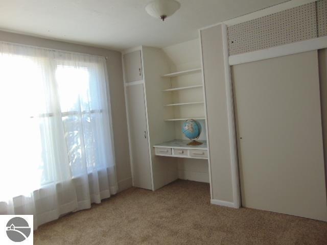 unfurnished bedroom with light colored carpet, a closet, and lofted ceiling