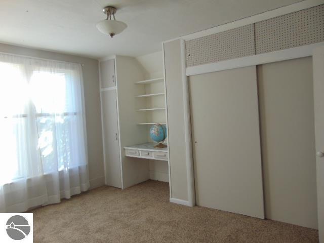 unfurnished bedroom featuring a closet, light colored carpet, and lofted ceiling