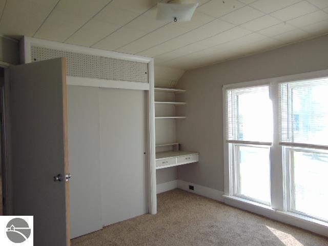 unfurnished bedroom featuring light colored carpet and vaulted ceiling