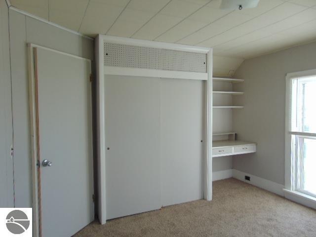 unfurnished bedroom with multiple windows, light colored carpet, and vaulted ceiling