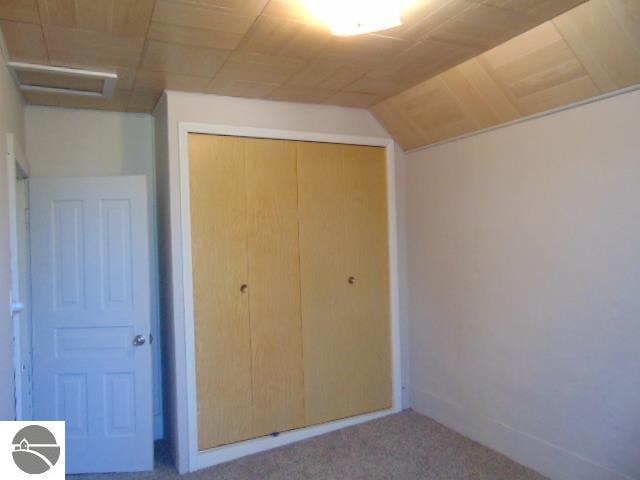 unfurnished bedroom featuring a closet, carpet, and vaulted ceiling