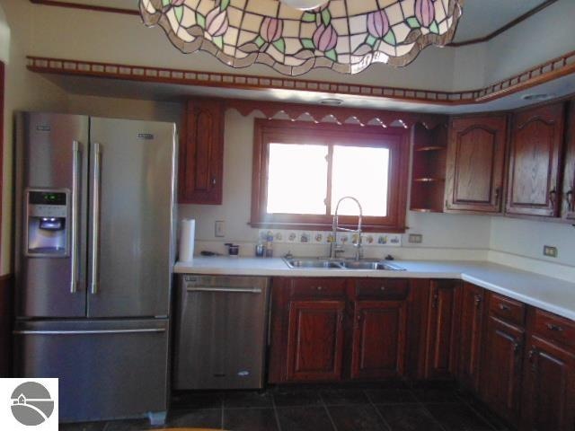 kitchen with sink, stainless steel appliances, and dark tile patterned flooring