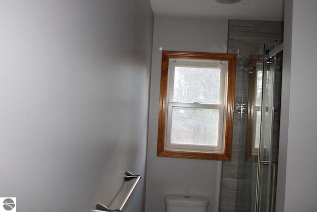 bathroom featuring toilet and a shower with door