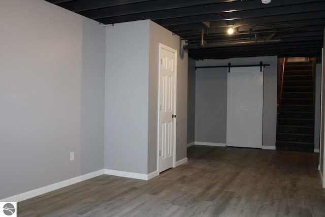 basement featuring a barn door and hardwood / wood-style flooring