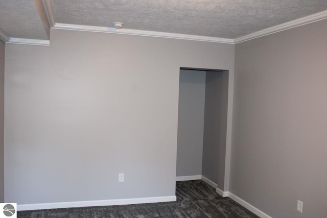 empty room with a textured ceiling, dark colored carpet, and crown molding